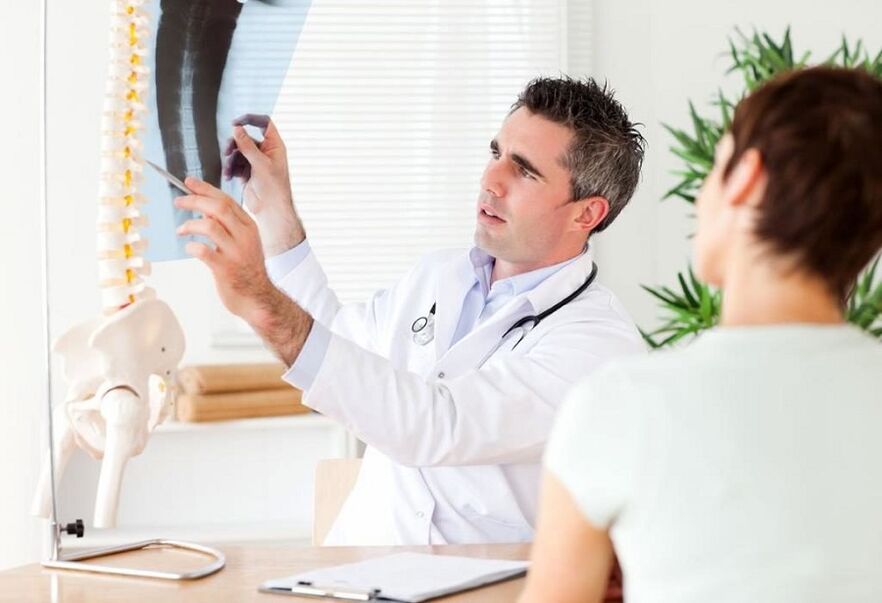 El médico examina una radiografía para diagnosticar la osteocondrosis torácica.